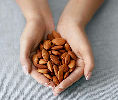 Raw Natural California Almonds in the hands on the grey ground by Anna and Sarah