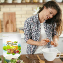 A woman holding two eggs to prepare something in the kitchen with Organic Walnuts resealable pack on the kitchen table by Anna and Sarah